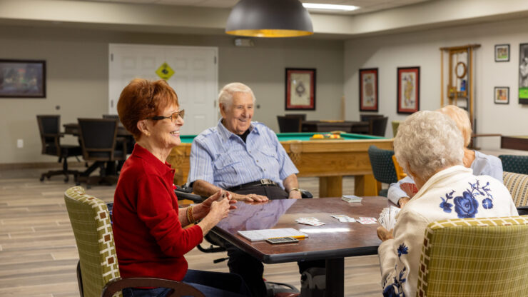 A lively group enjoys card games, sharing laughter and connection in a welcoming community space.