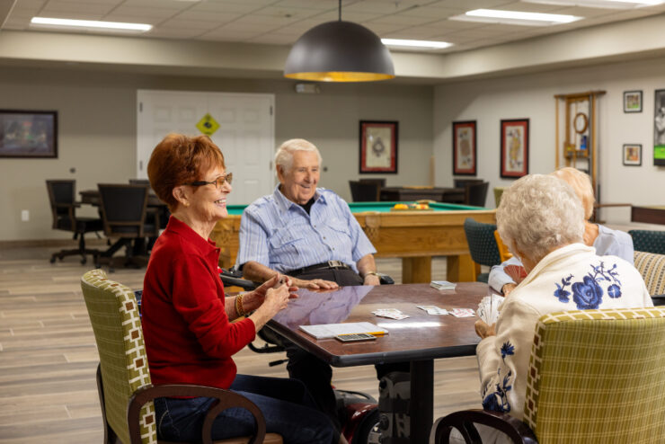 A lively group enjoys card games, sharing laughter and connection in a welcoming community space.