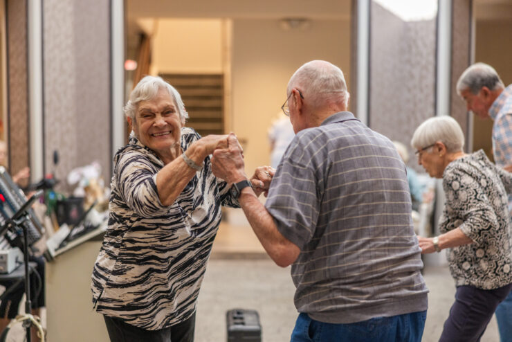 Residents joyfully dance together, celebrating community and connection in a vibrant atmosphere.