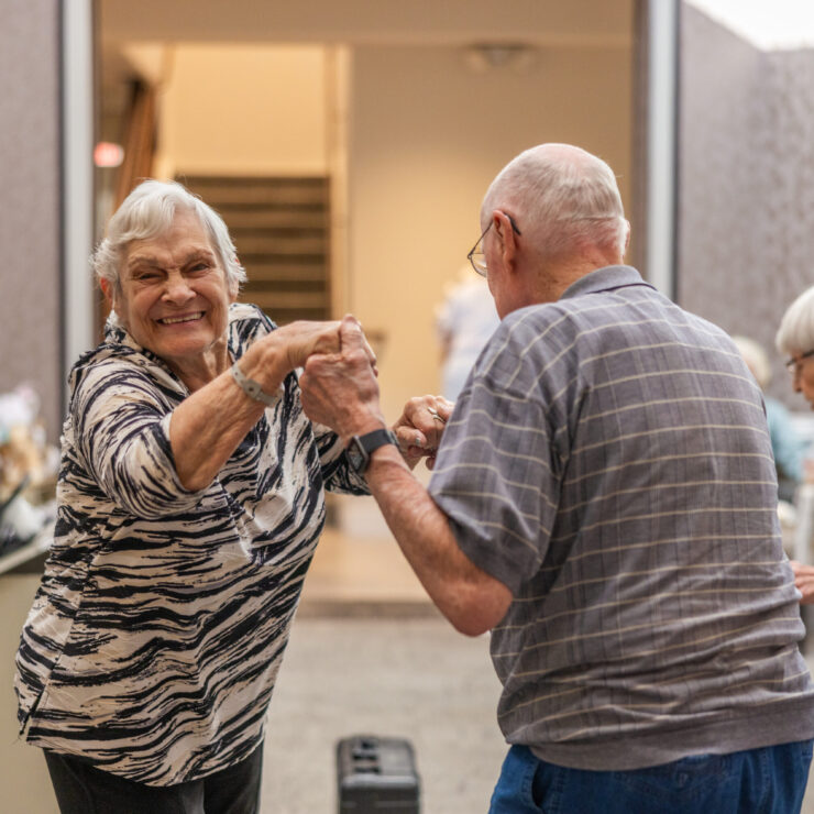 Residents joyfully dance together, celebrating community and connection in a vibrant atmosphere.