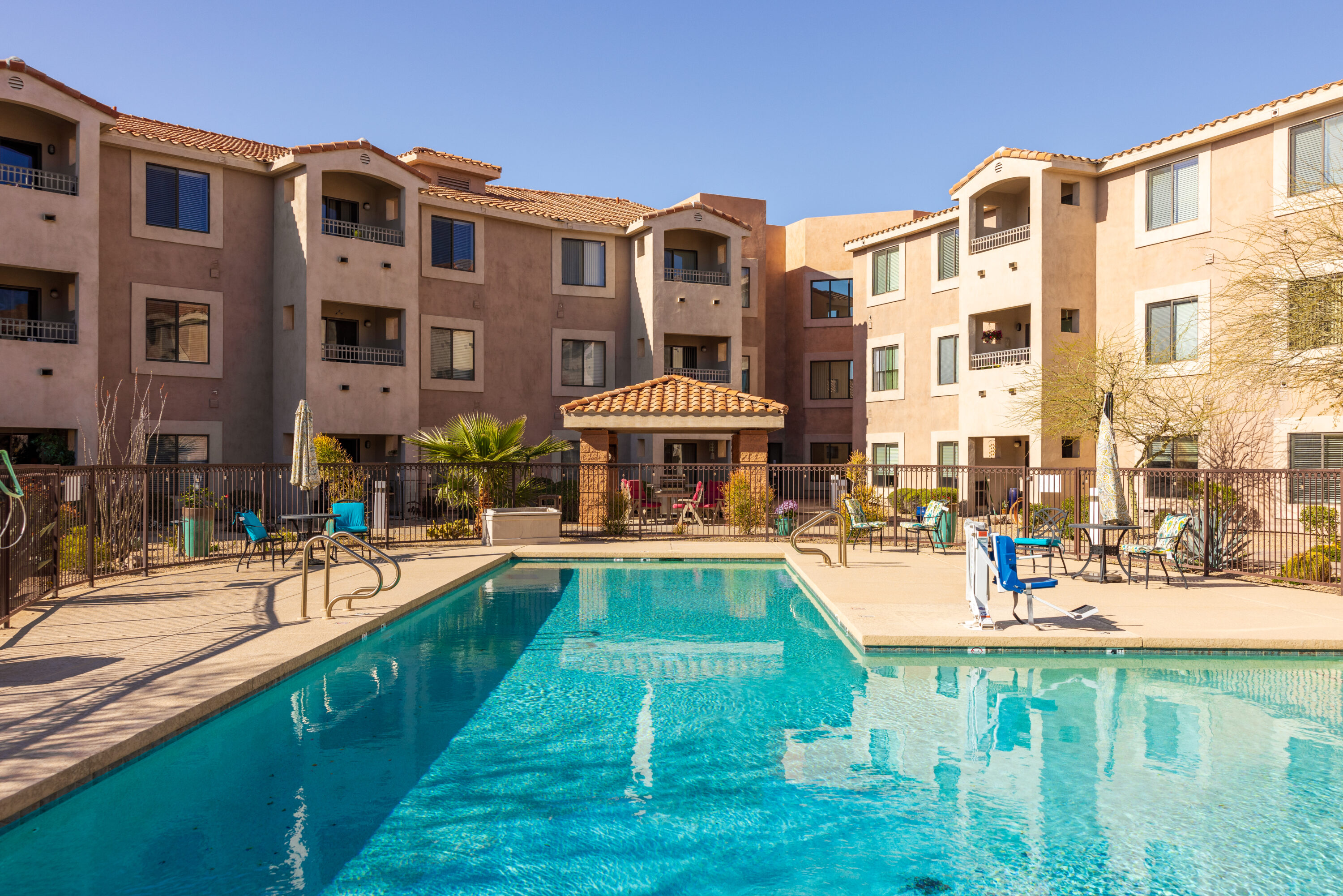 A welcoming pool area surrounded by vibrant greenery and comfortable seating, perfect for relaxation and community.