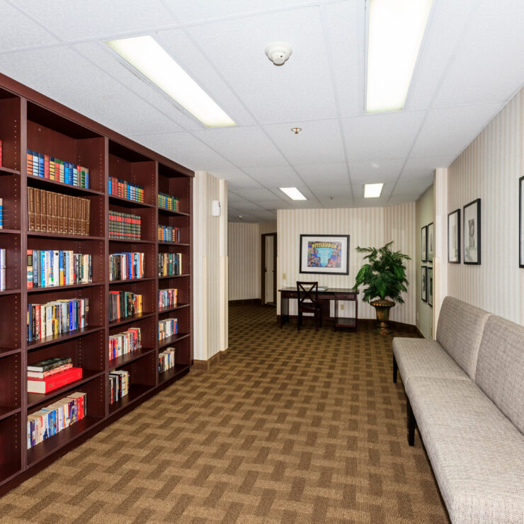 A welcoming hallway features a vibrant bookshelf, inviting seating, and framed art, enhancing community spirit.