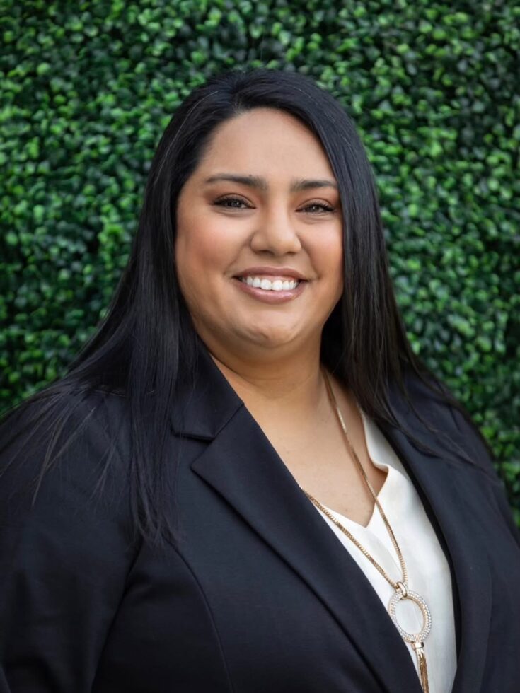 A warm smile against a lush green backdrop, embodying community and support in a welcoming environment.