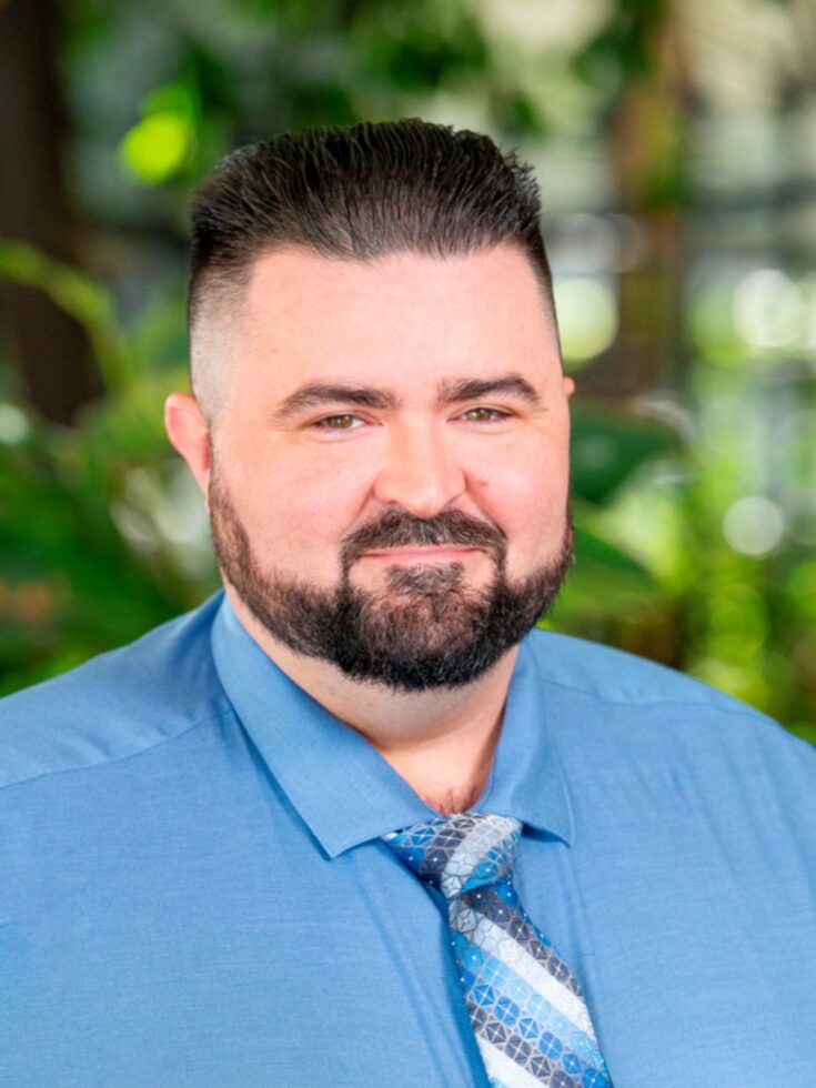 A welcoming smile in a vibrant, green setting reflects the warmth of our community.