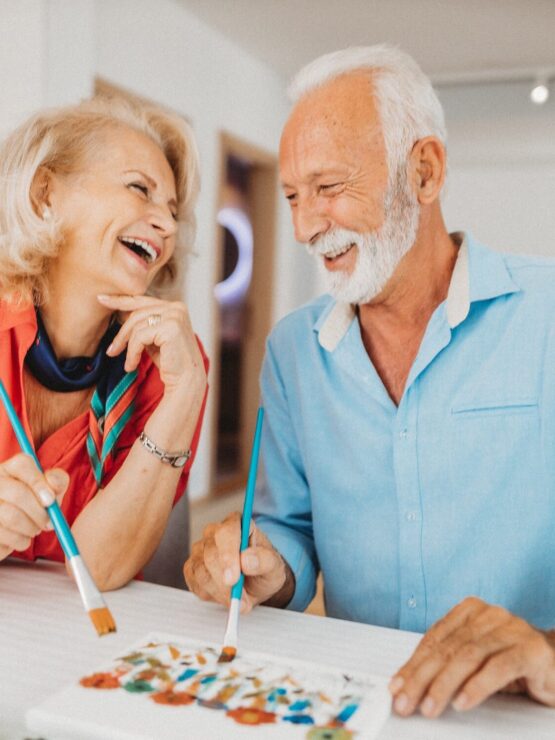 A joyful couple shares laughter while painting together, embodying community and creativity.