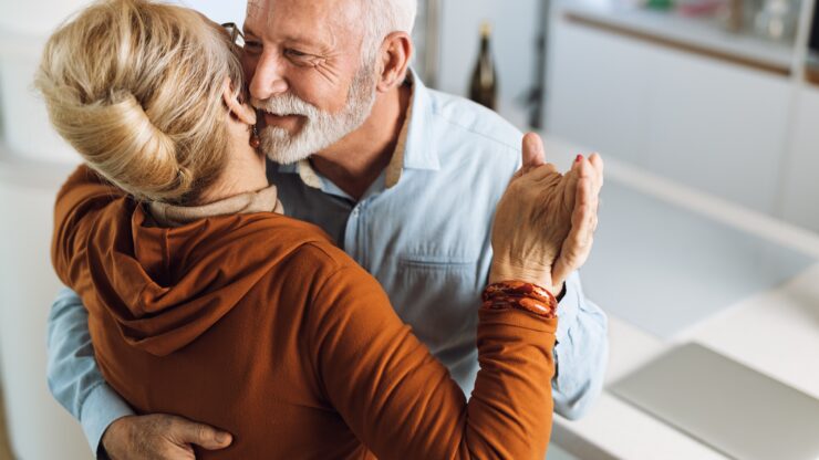 A joyful couple shares a heartfelt embrace, radiating warmth and connection in a welcoming home.