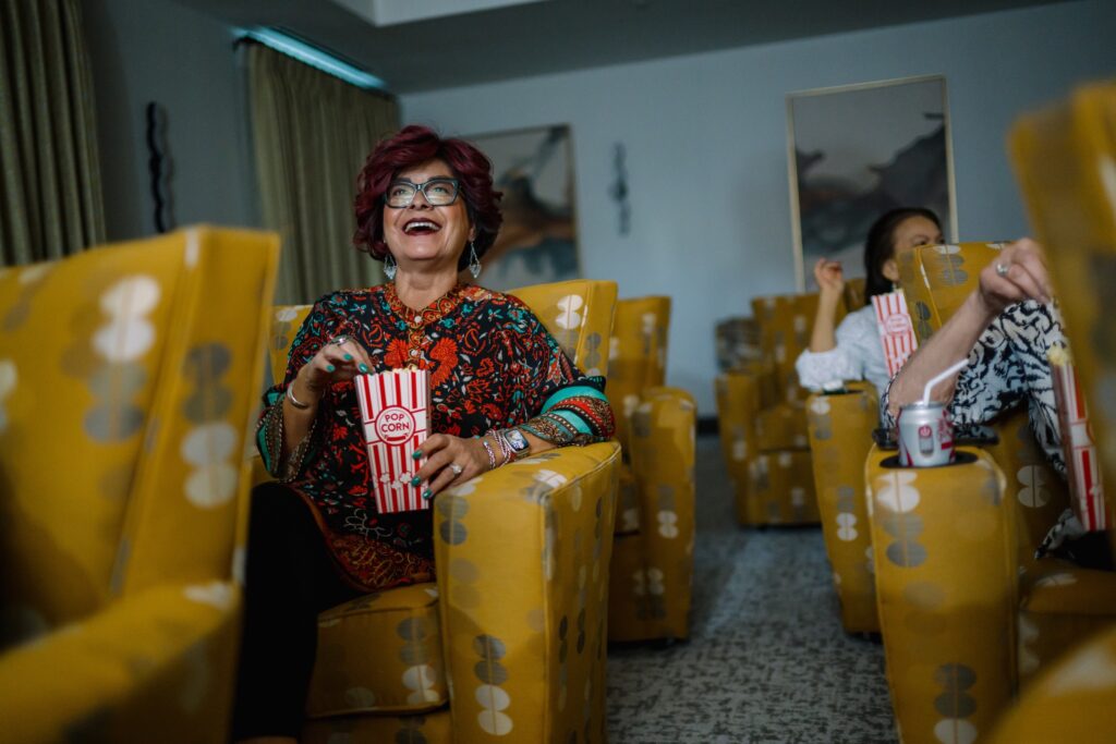 Residents enjoy a lively movie night, sharing laughter and popcorn in a vibrant, welcoming space.