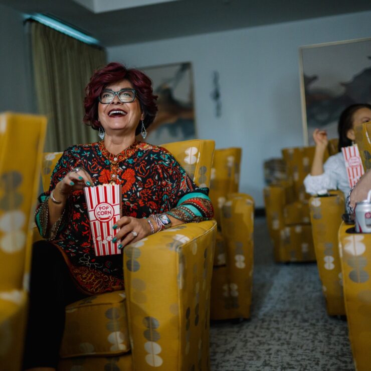 Residents enjoy a lively movie night, sharing laughter and popcorn in a vibrant, welcoming space.