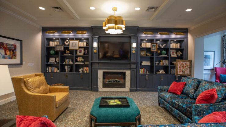 A welcoming lounge with vibrant seating, a warm fireplace, and shelves filled with books, perfect for socializing.