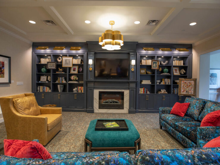 A welcoming lounge with vibrant seating, a warm fireplace, and shelves filled with books, perfect for socializing.