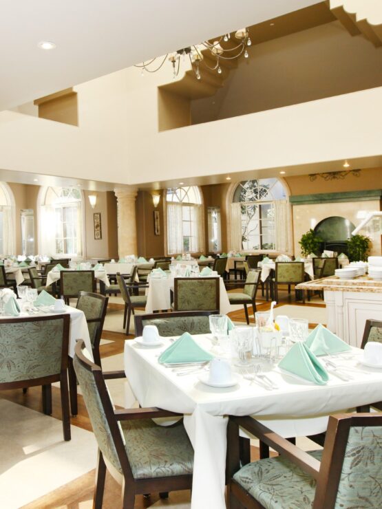 Bright and inviting dining area, featuring elegant tables and lush greenery, fostering community and comfort.