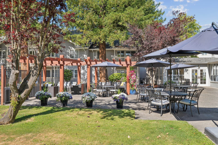 A welcoming outdoor space with shaded seating, blooming flowers, and a friendly atmosphere for gatherings.