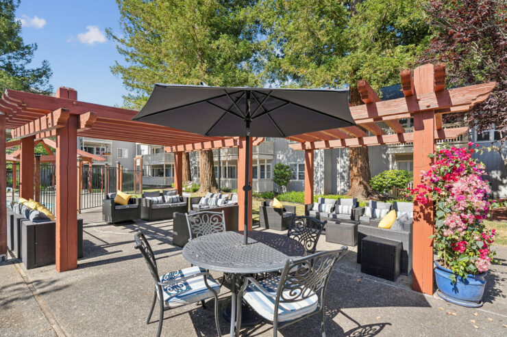 A serene outdoor space featuring comfortable seating, vibrant flowers, and inviting shade, perfect for community gatherings.