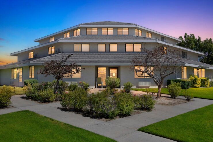 A welcoming retirement community, featuring lush gardens and a serene atmosphere under a twilight sky.