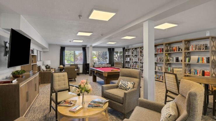 A welcoming lounge filled with comfortable seating, bookshelves, and natural light invites community and connection.
