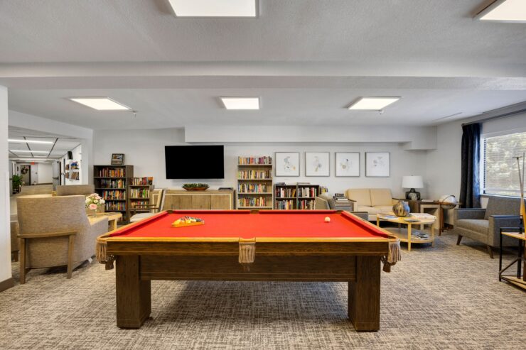 A vibrant game room inviting connection and fun, featuring a bright pool table and comfortable seating.