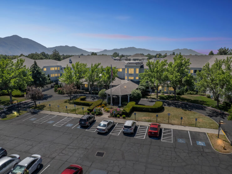 A welcoming retirement community surrounded by beautiful landscaping and serene mountains.