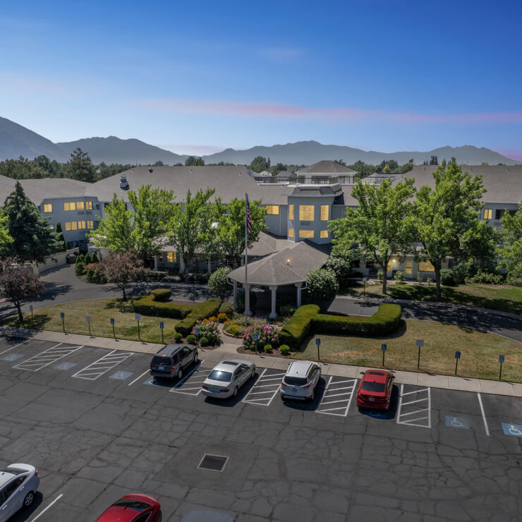A welcoming retirement community surrounded by beautiful landscaping and serene mountains.