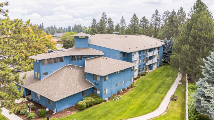 A welcoming community with beautiful blue buildings surrounded by lush greenery and pathways.