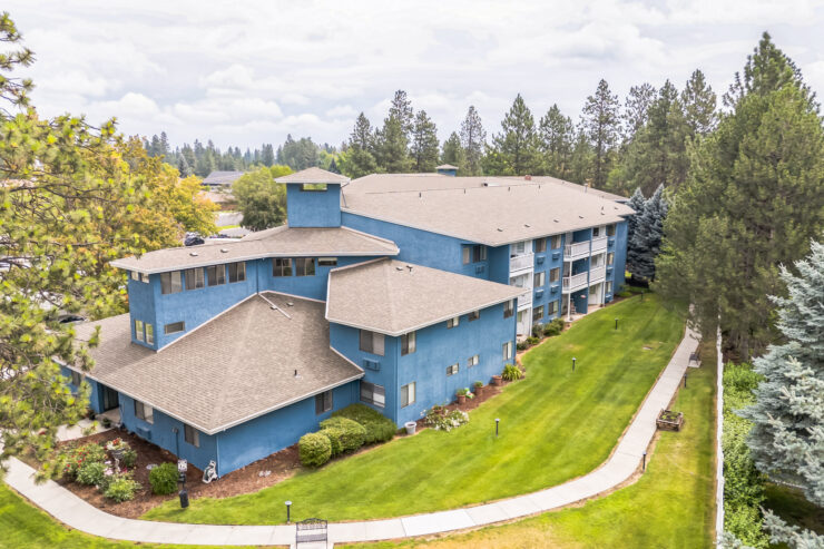 A welcoming community with beautiful blue buildings surrounded by lush greenery and pathways.