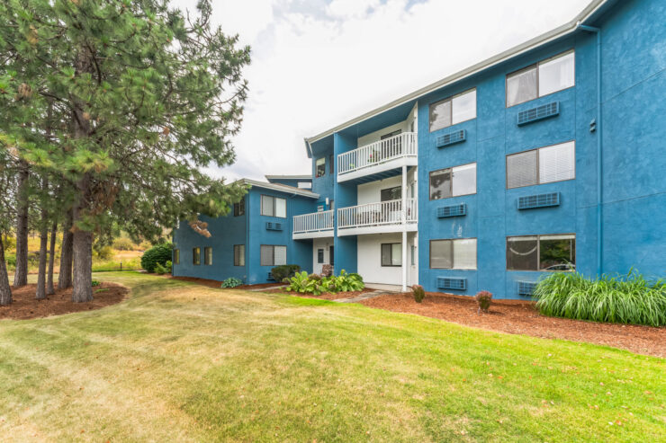 A welcoming community space featuring a vibrant blue building surrounded by lush greenery.