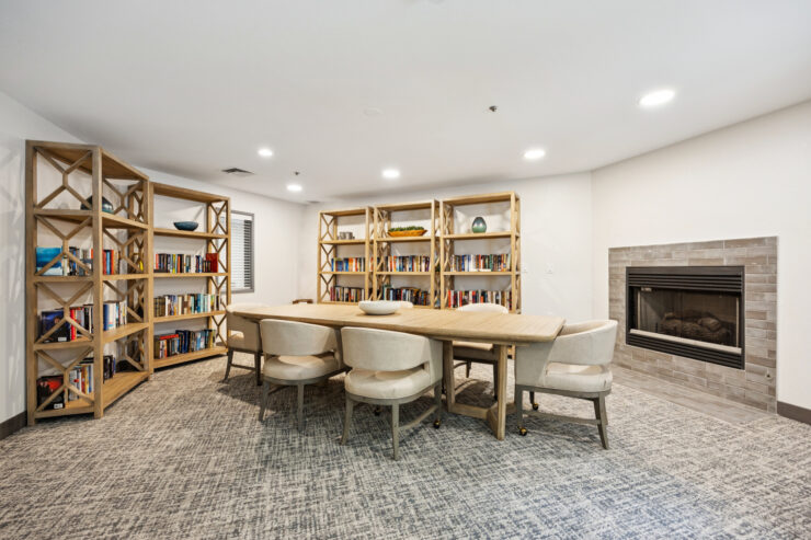 A welcoming gathering space with bookshelves, a warm fireplace, and comfortable seating for community connection.