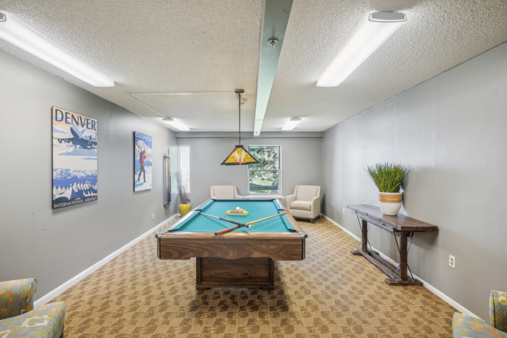 A welcoming game room featuring a pool table, comfortable seating, and cheerful decor, inviting community interaction.