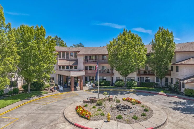 A welcoming community center surrounded by lush trees and vibrant gardens, inviting connection and comfort.