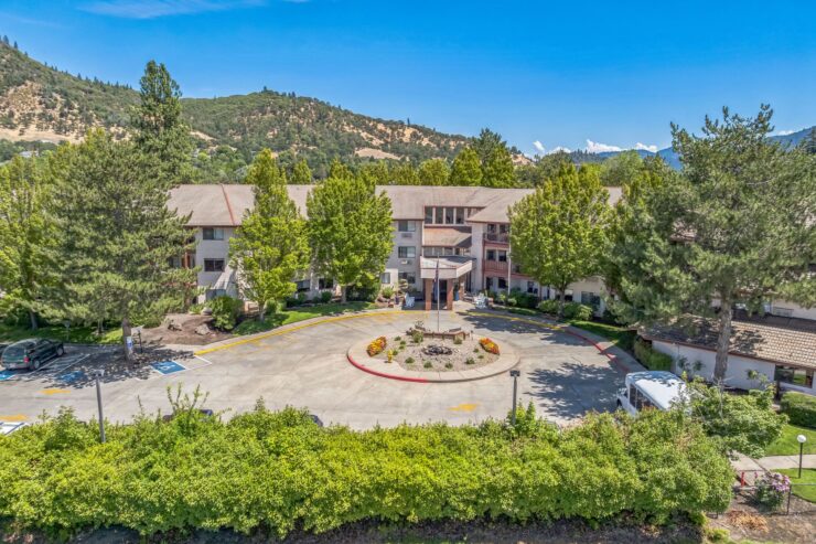 A welcoming retirement community surrounded by lush greenery and beautiful mountains, fostering connection and comfort.