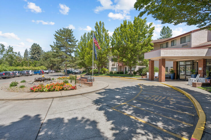 A welcoming entrance surrounded by vibrant gardens and trees, embodying community and tranquility.