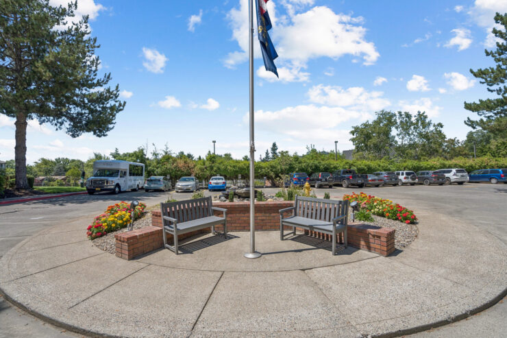 A welcoming outdoor space with benches, vibrant flowers, and a flag, perfect for community gatherings.