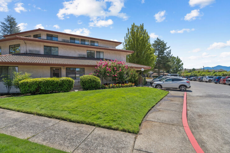 A welcoming entrance features lush greenery and vibrant flowers, inviting a warm community atmosphere.