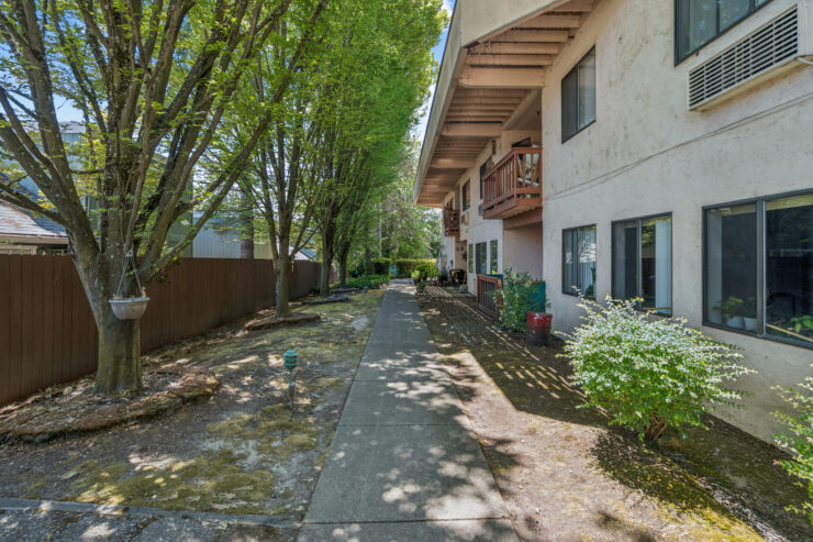 A serene pathway lined with greenery invites residents to enjoy a peaceful outdoor community space.