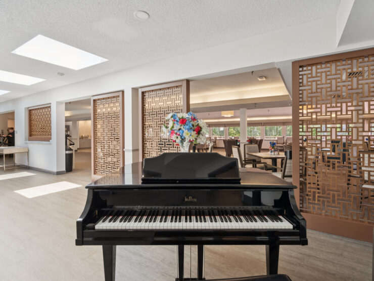 A welcoming space filled with natural light, featuring a piano and vibrant flowers, encourages community interaction.
