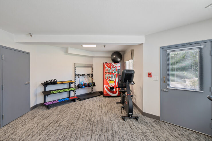 A bright, inviting fitness area equipped with exercise machines and weights, promoting wellness and community.