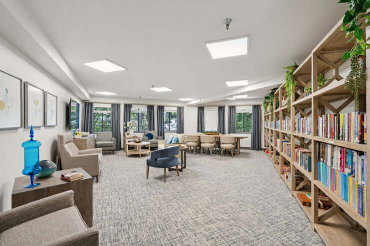 A welcoming lounge filled with natural light, inviting seating, and a well-stocked bookshelf for community engagement.