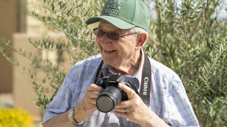 A cheerful resident enjoys capturing moments, surrounded by nature's beauty, fostering community spirit.