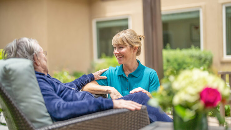 A warm interaction in a serene outdoor setting, highlighting community and care among residents and staff.