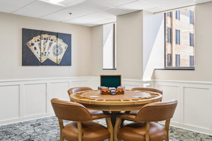 A welcoming game room features a round table, comfortable chairs, and natural light, inviting social interaction.