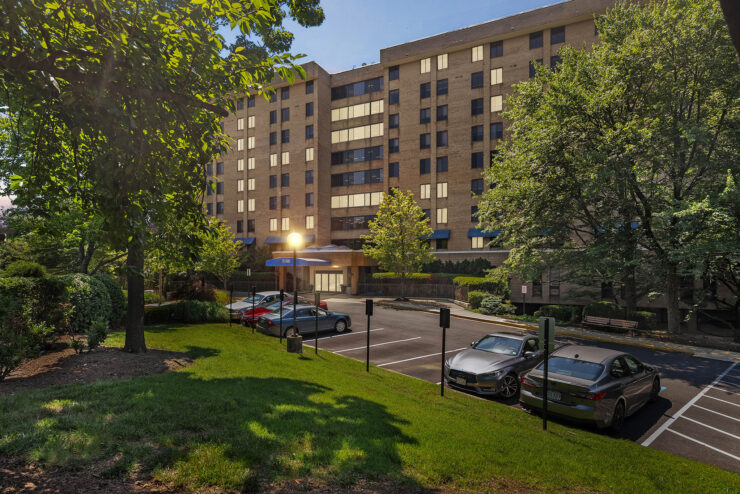 A welcoming retirement community surrounded by lush greenery and ample parking, perfect for residents.