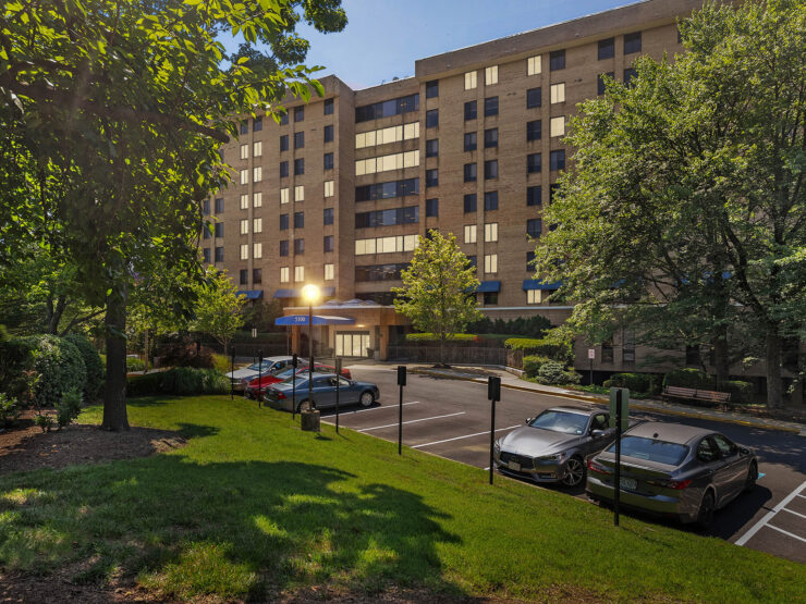 A welcoming retirement community surrounded by lush greenery and ample parking, perfect for residents.