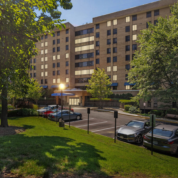 A welcoming retirement community surrounded by lush greenery and ample parking, perfect for residents.