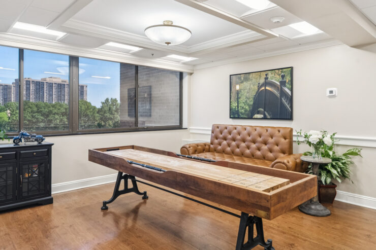 A warm, inviting space with natural light, featuring a comfortable couch and engaging game table for community fun.