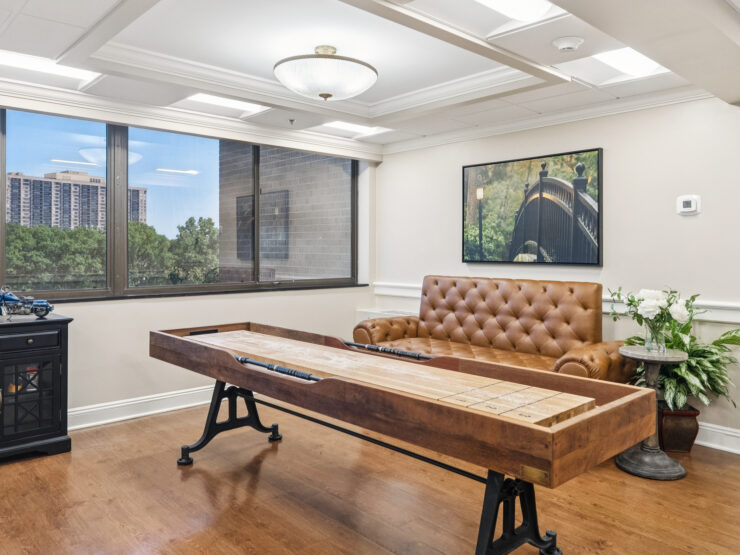 A warm, inviting space with natural light, featuring a comfortable couch and engaging game table for community fun.