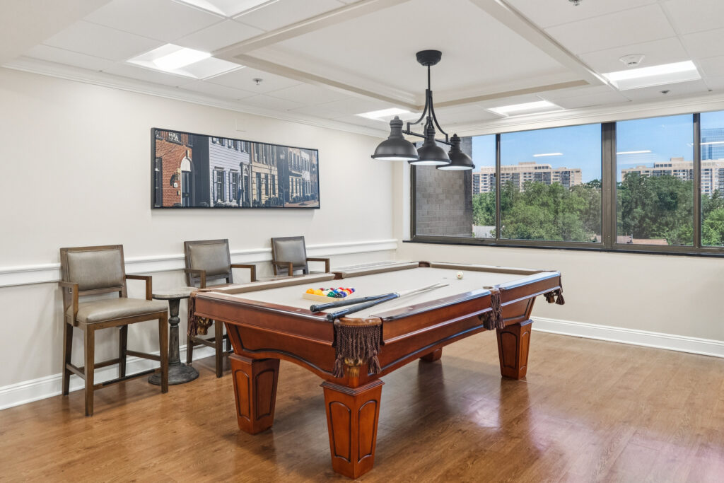 A welcoming game room with a pool table, inviting seating, and bright natural light, perfect for socializing.
