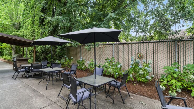 A serene outdoor space with shaded tables invites relaxation and connection in a vibrant community.