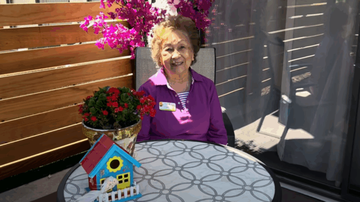 A cheerful resident enjoys the vibrant outdoor space, surrounded by blooming flowers and a welcoming atmosphere.