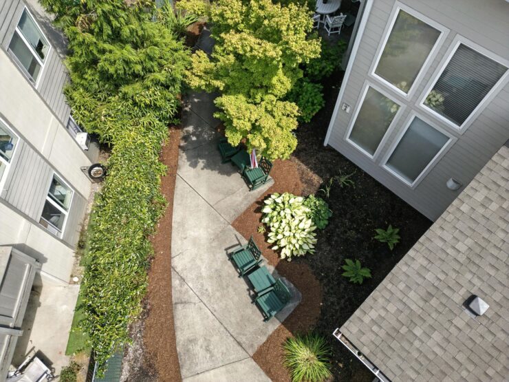 A serene garden pathway invites relaxation, surrounded by lush greenery and comfortable seating.