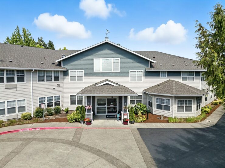 A welcoming retirement community, featuring a bright exterior and inviting entrance, surrounded by nature.