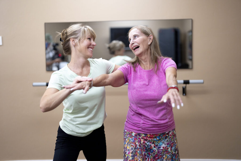 Two women joyfully engage in a dance class, embodying community spirit and vibrant energy.